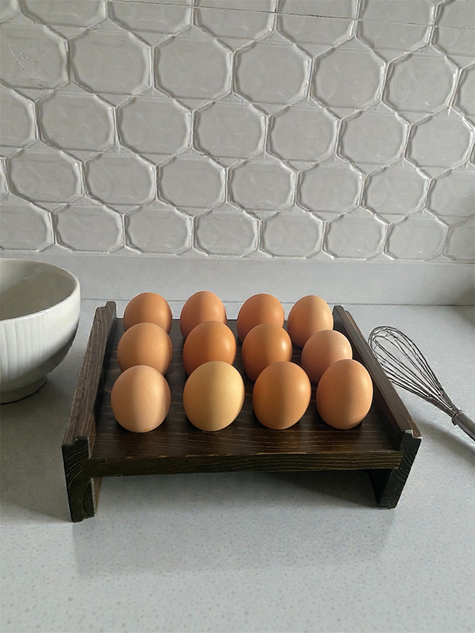 Wooden tray with eggs on a kitchen counter with a tiled wall background